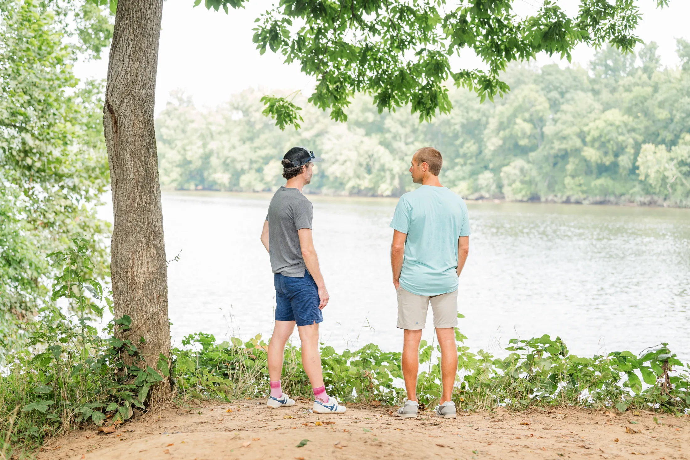 Two men standing at the edge of the James River in soft summer light