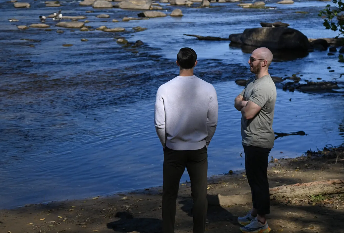 Two men standing at the edge of the James River in conversation